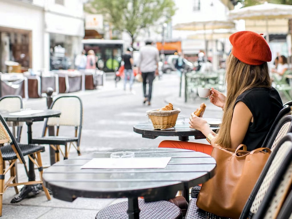 French girl eating baguette and croissant on a terrace in Paris - Paris Whatsup